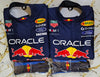 A navy blue Oracle Racing team apparel set laid flat on a light marble surface, including a sleeveless top with large Oracle and Red Bull graphics, a matching headband, and a pair of gloves in plastic packaging. Visible sponsor logos include Oracle, Red Bull, TAG Heuer, Ford, and BACH.